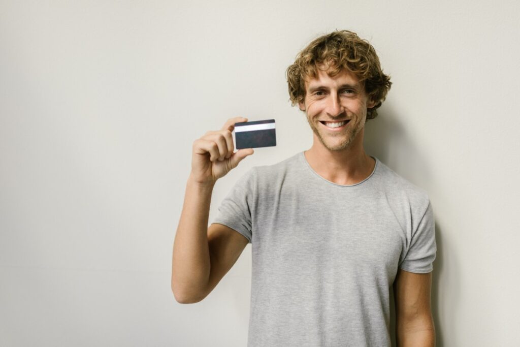 homme souriant avec une carte de crédit