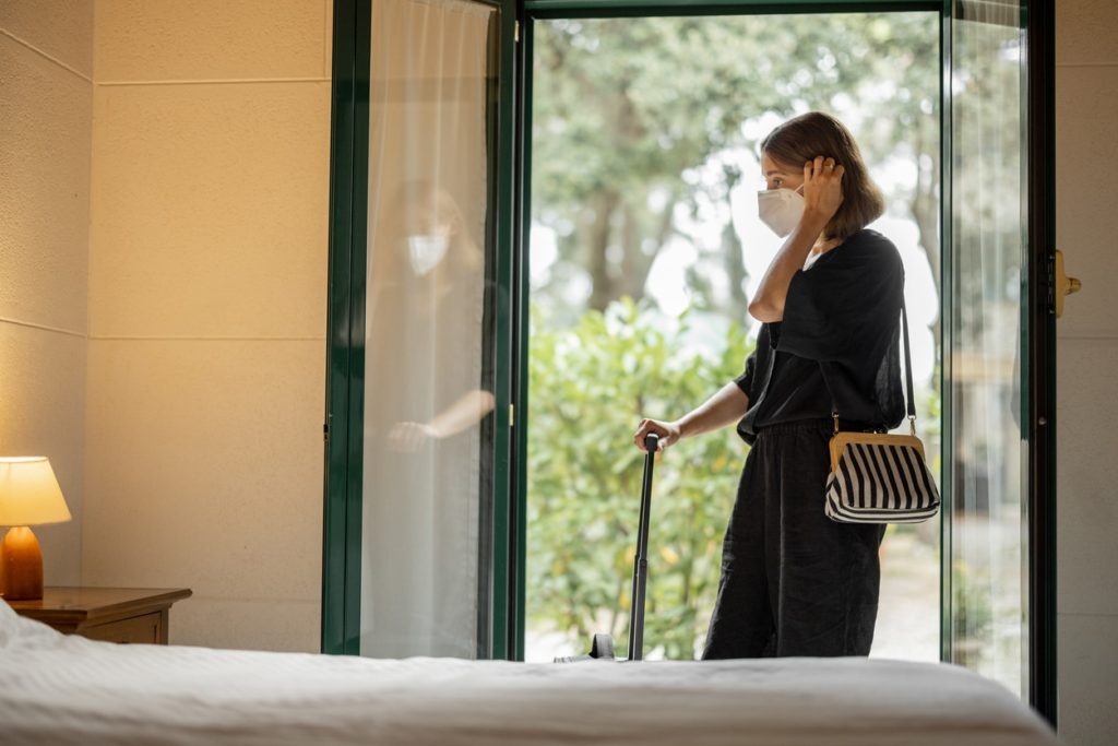 Femme portant un masque médical entrant dans une chambre d'hôte