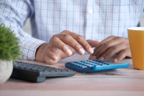 Homme utilisant une calculette à côté d'un clavier