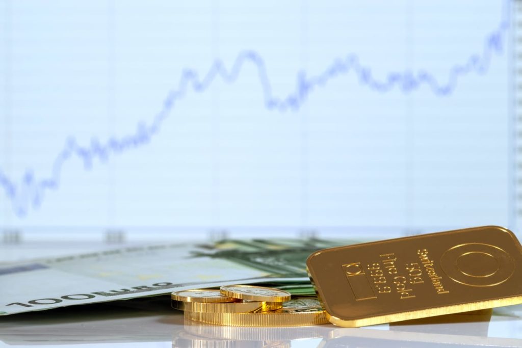 Barre d'or, pièces de monnaie et un billet de cent euros sur le fond du tableau de croissance