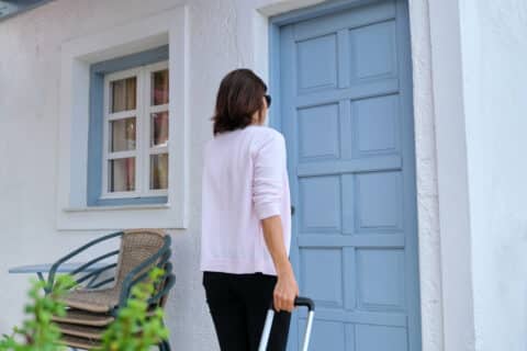 Une femme avec valise arrivant dans une location saisonnière