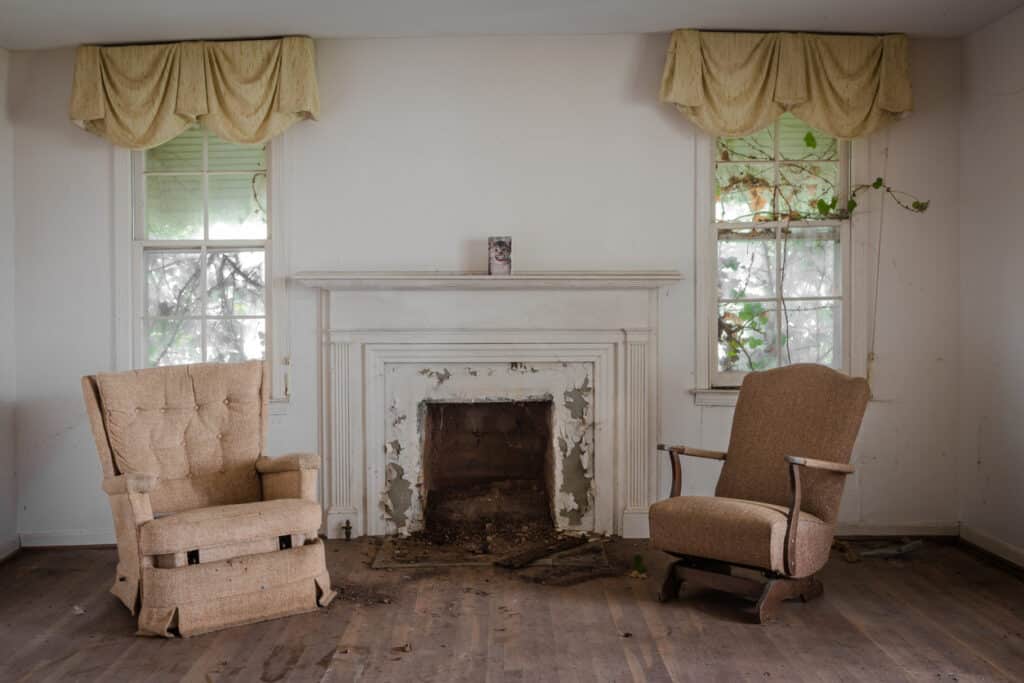 Salon avec deux chaises avec une cheminée dans une maison délabrée