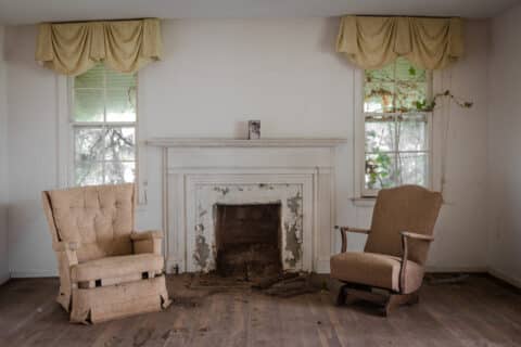 Salon avec deux chaises avec une cheminée dans une maison délabrée
