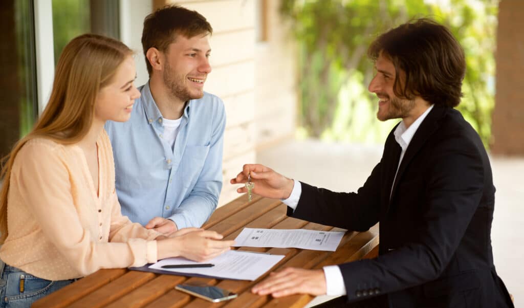 Courtier immobilier donnant la clé de maison à un couple