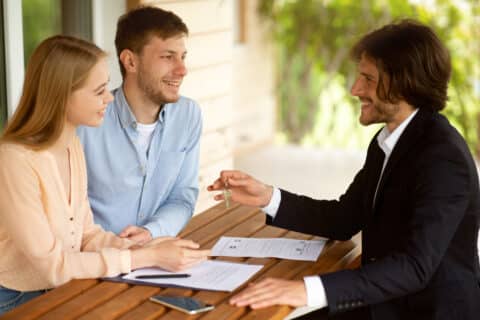 Courtier immobilier donnant la clé de maison à un couple
