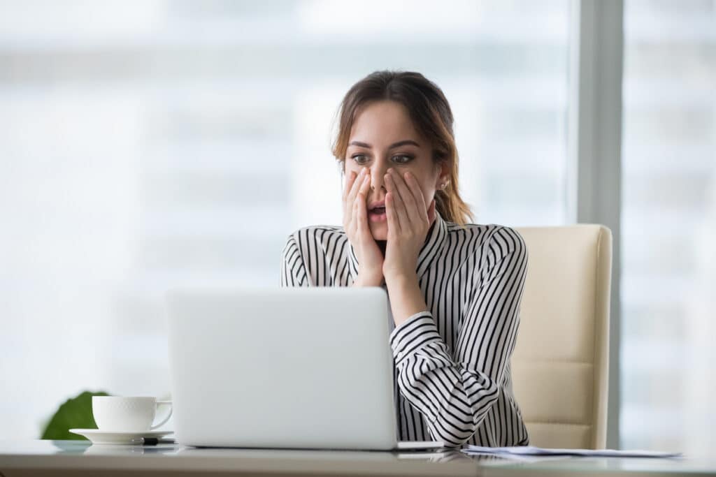 Jeune femme d'affaire choquée devant son ordinateur portable
