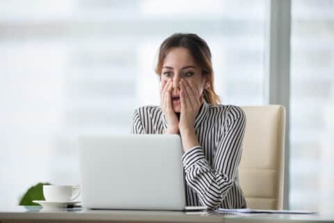 Jeune femme d'affaire choquée devant son ordinateur portable