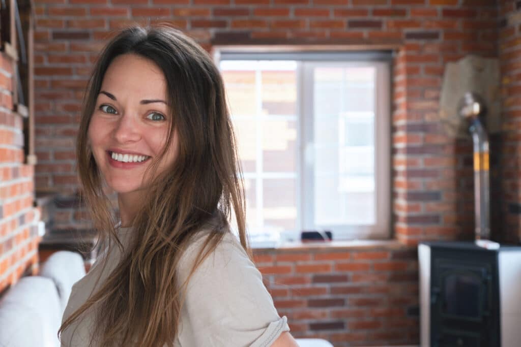 Femme souriante dans sa maison en brique rouge