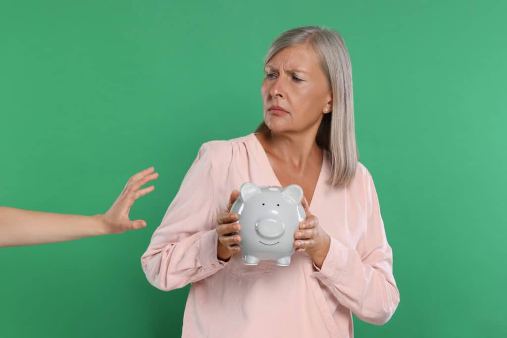 Escroc prenant la tirelire d'une femme agée sur fond vert