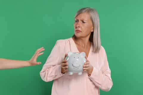 Escroc prenant la tirelire d'une femme agée sur fond vert