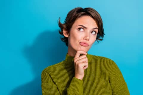 Femme indécise sur fond de couleur cyan