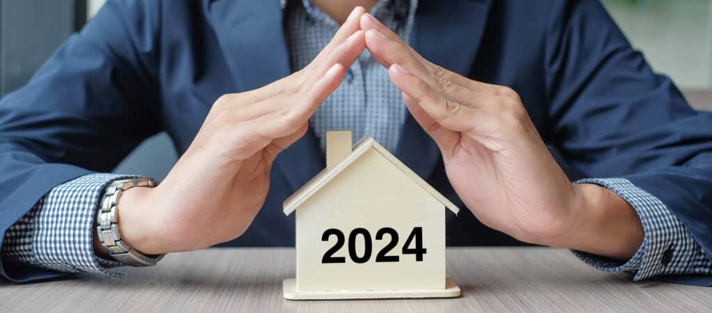 Homme d'affaires avec une maison en bois avec le texte 2024