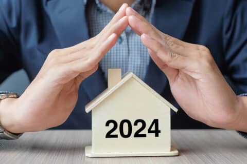Homme d'affaires avec une maison en bois avec le texte 2024