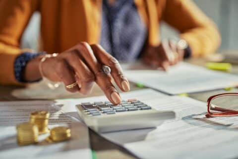 Black womaRéduisez vos impôts en 2024 : les meilleures stratégies à connaître !n hand calculating taxes
