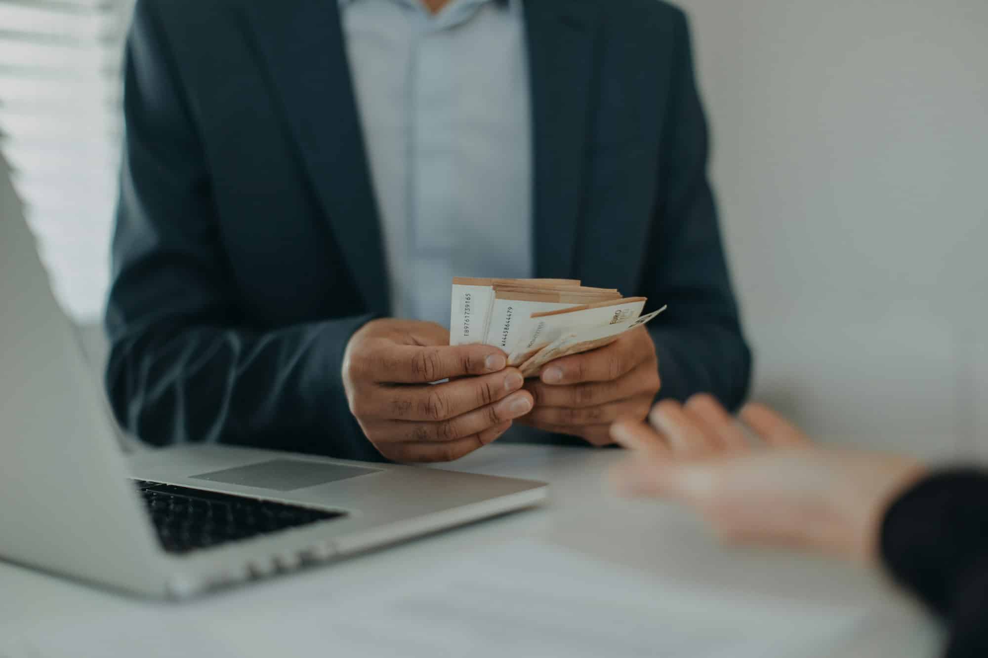 Businessman giving money to his partner while making contract - bribery and corruption concepts