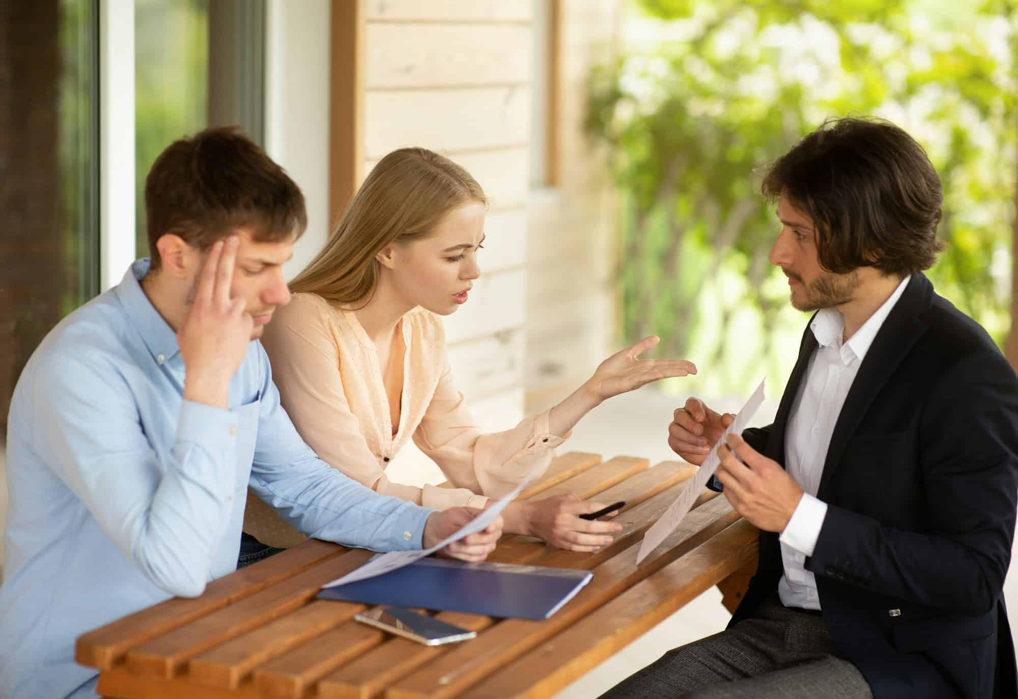Famille millénaire déçue par les mauvaises conditions de location et le gestionnaire immobilier à table sur le porche de la maison