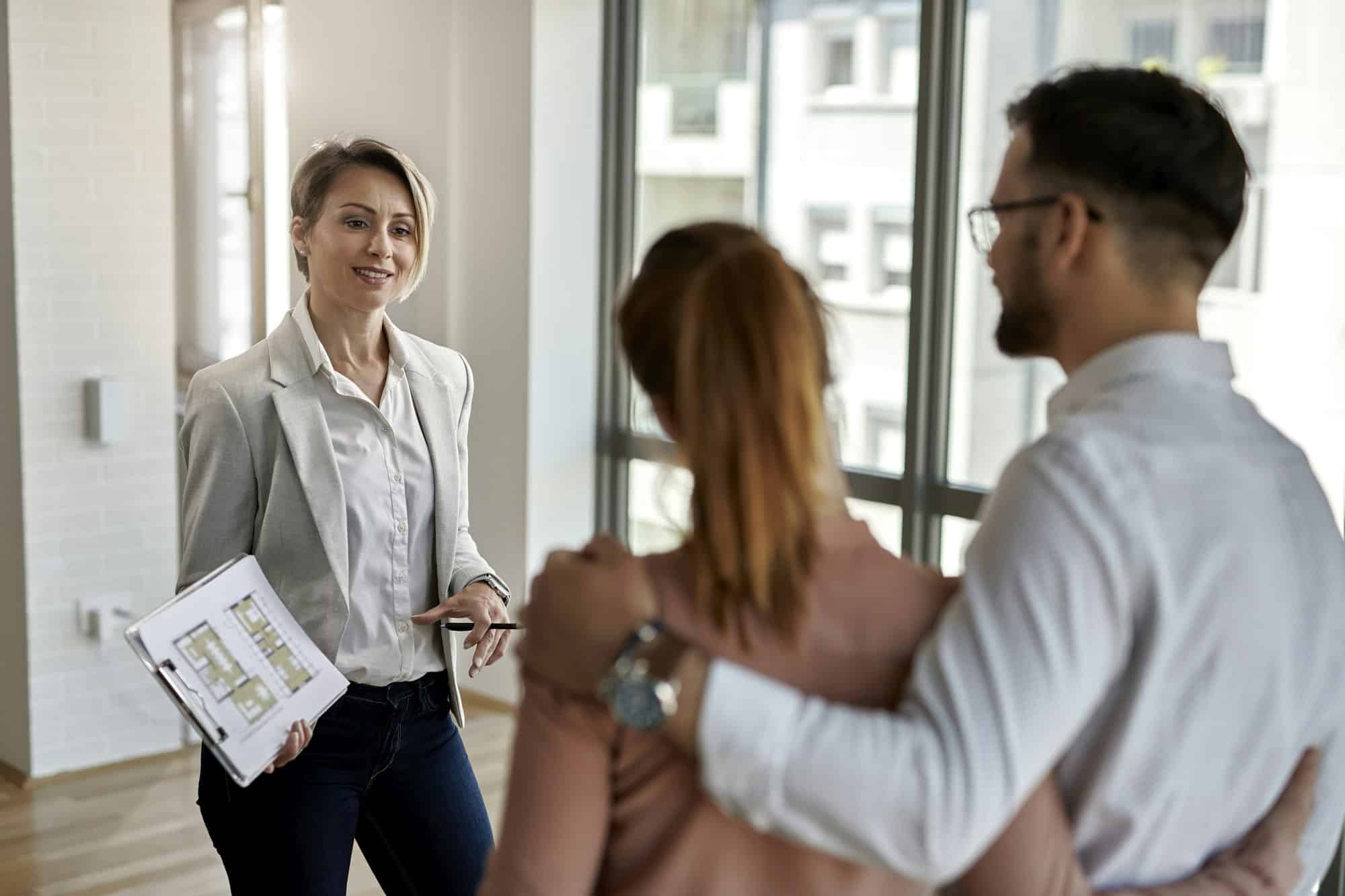 Agent immobilier parlant à un couple intéressé à acheter une nouvelle maison.