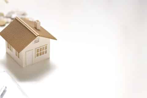 Photo of house model, clipboard, saving money in vase putting together on white table.