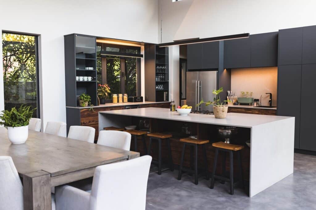 Les tendances 2024 pour des maisons contemporaines : design et durabilité kitchen with large island, bar stools, and dining table in contemporary home