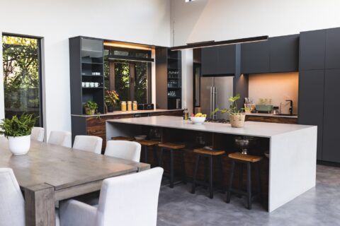 Les tendances 2024 pour des maisons contemporaines : design et durabilité kitchen with large island, bar stools, and dining table in contemporary home